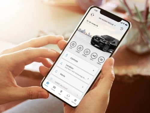 2024 Nissan Rogue view of woman holding phone with MyNissan app shown