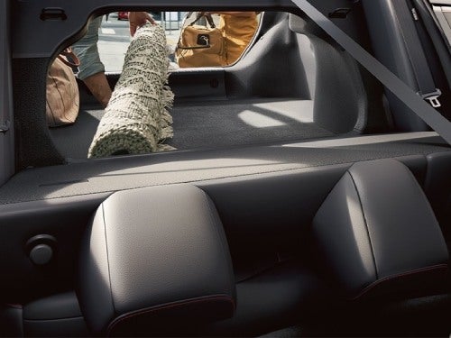 2024 Nissan Sentra view of back seat laid down and trunk open while person loads a rug into trunk